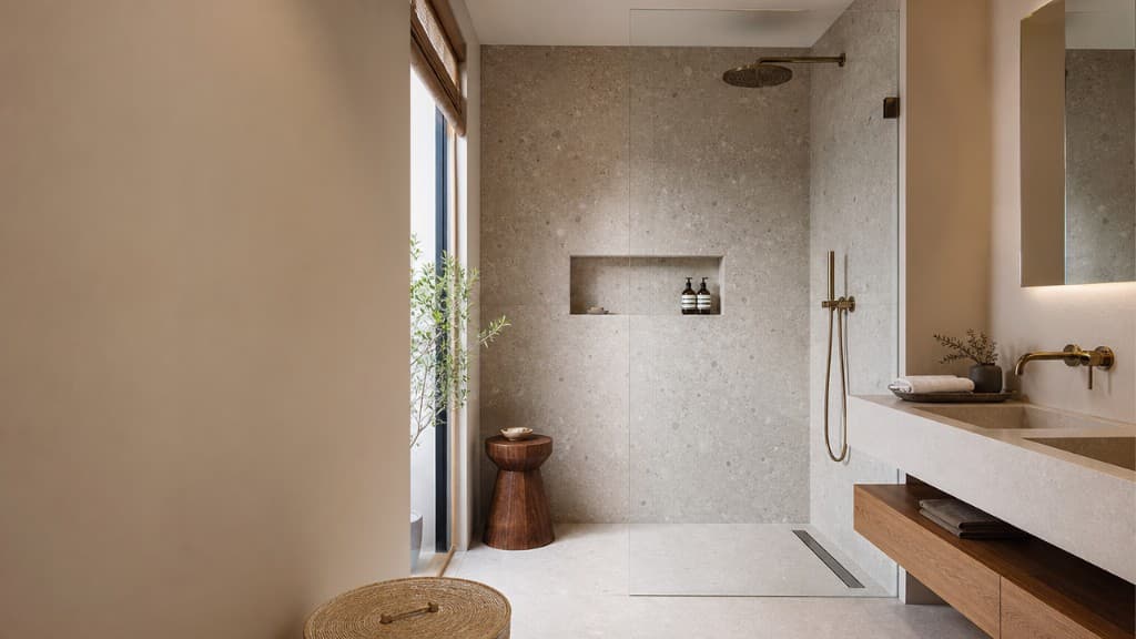 Baño de piso con ducha de obra, mampara de cristal y lavabo doble integrado