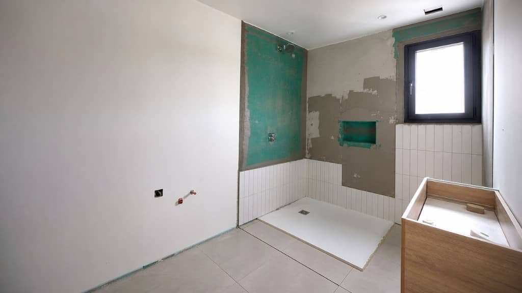 Baño en obra con impermeabilización, plato de ducha y alicatado en proceso